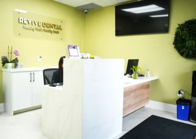 Revive Dental Clinic Front Desk Area at Revive Dental Mississauga featuring a modern reception counter, Revive Dental wall sign, TV, and welcoming clinic interior.