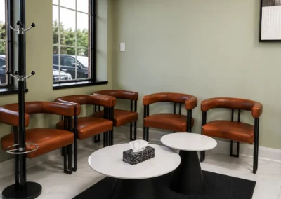 Revive Dental Clinic Reception waiting area at Revive Dental Mississauga with brown chairs, round tables, large windows, and a coat rack.