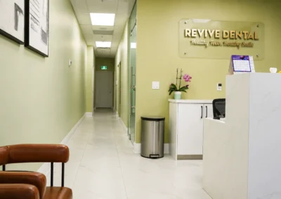 Revive Dental Clinic Enterance at Revive Dental Mississauga featuring a modern reception desk, clinic hallway, seating area, and Revive Dental wall sign.